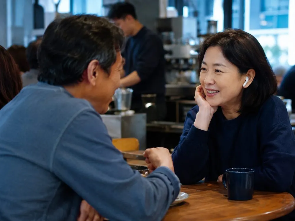 시끄러운 카페에서 이어폰을 끼고 마주 앉은 상대와 대화하는 모습